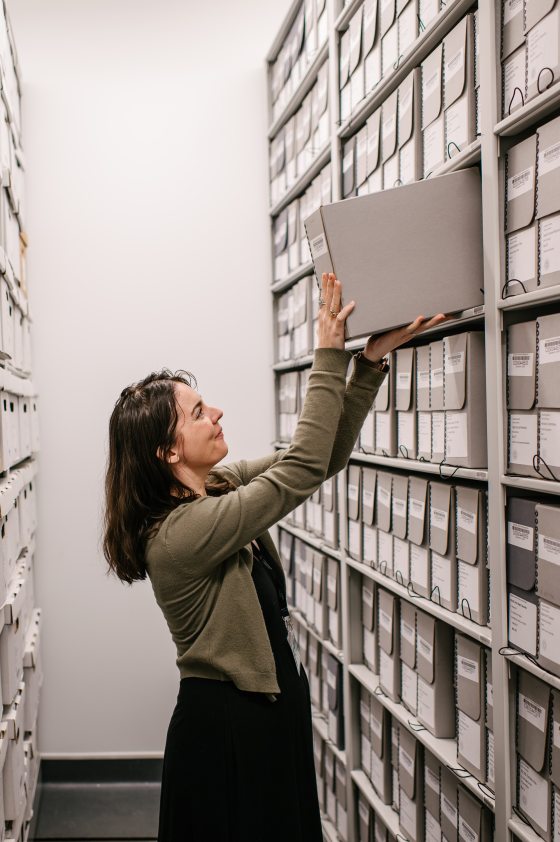 A person putting an archive box away on a shelf.